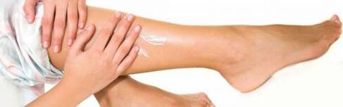 Applying medicinal cream to legs with dilated veins